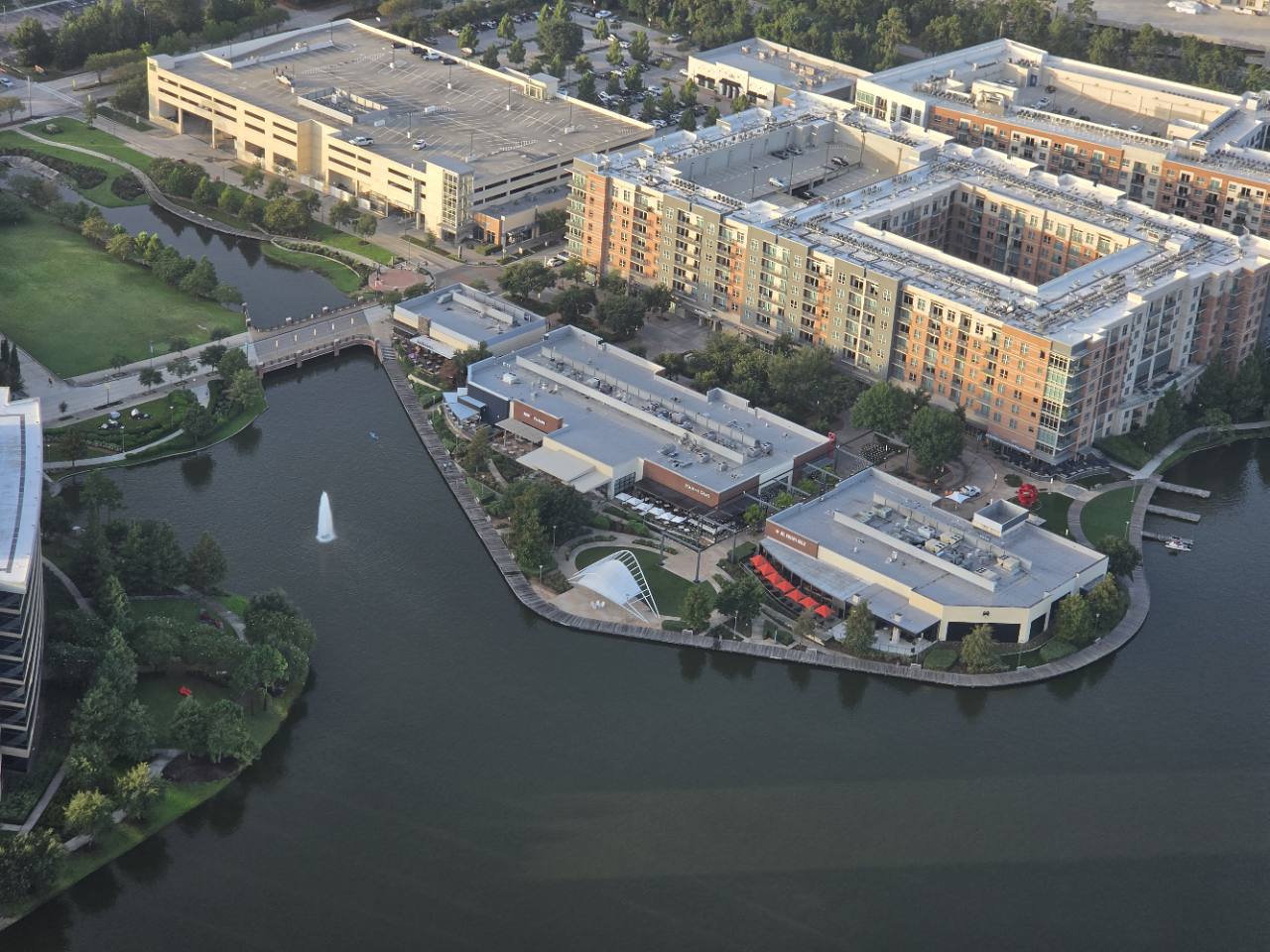 Aerial view of waterfront dining, residences, and green space in The Woodlands